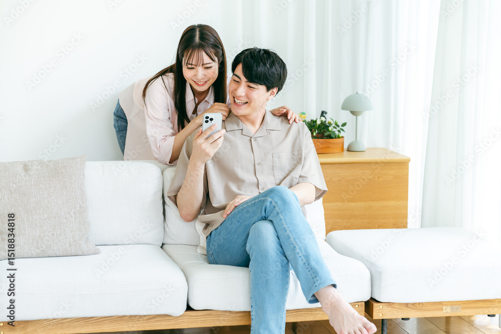 Obraz premium リビングでスマホを見るカップル