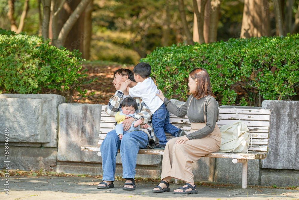 In March, at a sunny park in Fukuoka, a Japanese couple in their thirties sits on a bench with their 3-year-old son and baby girl, 6 months old. This photo captures a peaceful family moment outdoors. In March, at a sunny park in Fukuoka, a Japanese couple in their thirties sits on a bench with their 3-year-old son and baby girl, 6 months old. This photo captures a peaceful family moment outdoors.