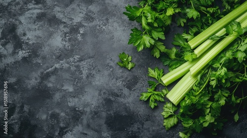 Fresh celery stalks and parsley leaves on a dark background.