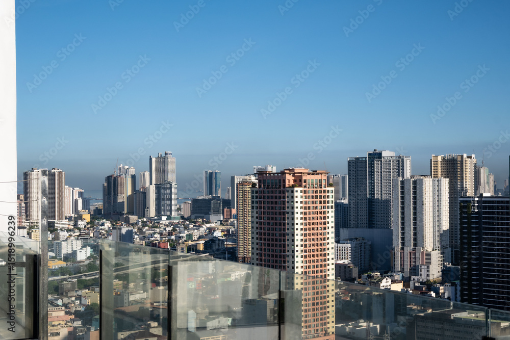 Fototapeta premium The cityscape of Manila skyline with high-rise buildings surrounded by lush greenery outdoor at daytime with blue sky.on the rooftop of a hotel during a holiday in the Philippines in South East Asia.