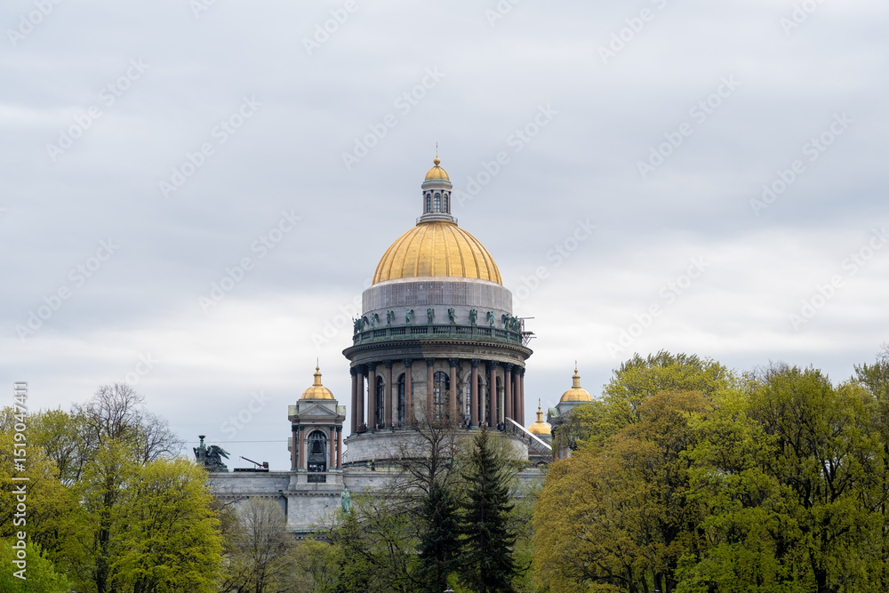 Fototapeta premium St. Isaacs Cathedral With Golden Dome Surrounded by Lush Greenery in Overcast Weather