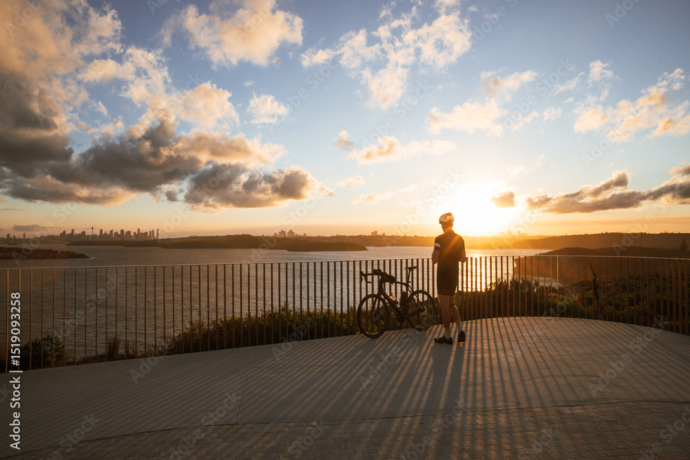Fototapeta premium Cyclist admiring sunset over sydney harbour at north head in manly