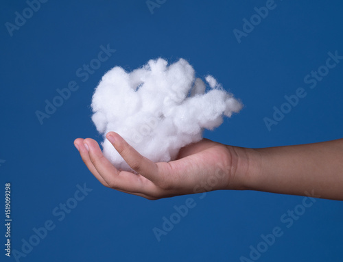 Siliconized hollowfiber, polyester fiber cloud held in a hand against a blue background