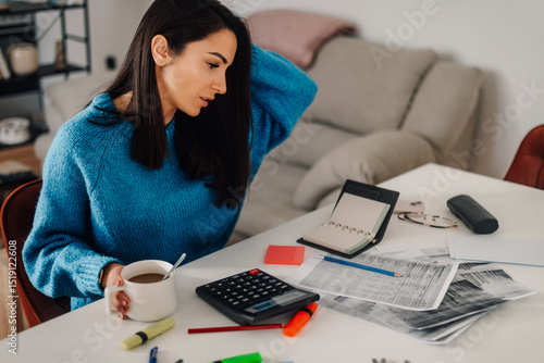 Canvas Print Stressed young woman managing home finances and calculating bills at table