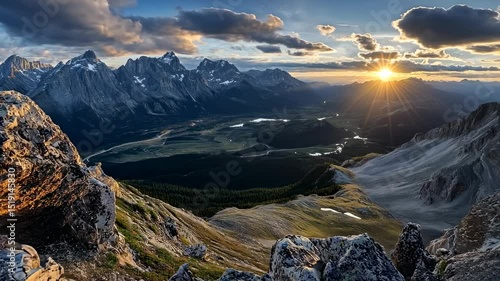 Majestic mountain panorama at sunset, showcasing a valley, rocky foreground, and sun rays