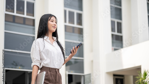 Asia woman in shirt holding phone and laptop standing or alking out of university or office building Free Download Asia woman in shirt holding phone and laptop standing or alking out of university or office building - GFXLoad
