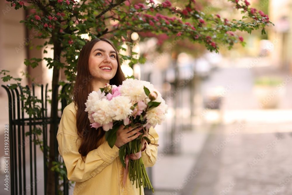 Fototapeta premium Woman with bouquet of beautiful peonies on city street. Space for text