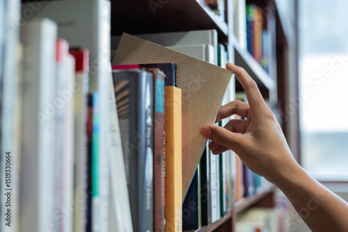right hand choosing and picking book in public library.
