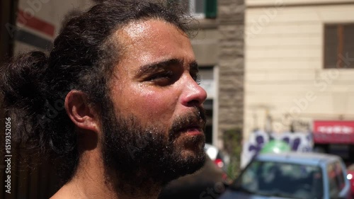 A young man struggles with high temperatures, sweating and fanning himself on a hot city day