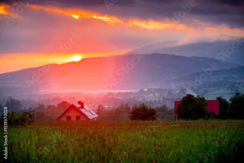 Fototapeta Naklejka Na Ścianę i Meble -  Beautiful picturesque sunset on the meadow with a view of the cottage and the Beskidy Mountains, Poland.