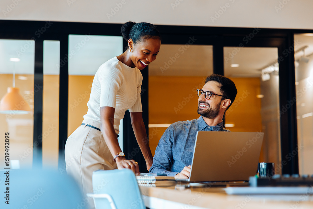 Colleagues interacting and smiling during a casual discussion in an office environment Colleagues interacting and smiling during a casual discussion in an office environment