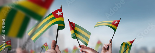 Photos Togo flags in their hands on a blurred urban background