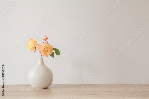 yellow roses in ceramic vase on wooden table