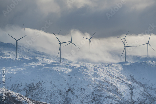 Panorama with wind park over the mountains from the island of Kvaløya, Norway, with many wind turbines. Windmills in winter on the coast of the Atlantic produce electricity.