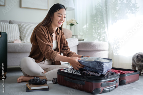 Traveler organizing luggage in living room with packing cubes and travel essentials.