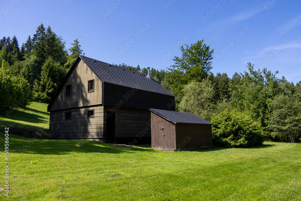 Obraz premium Old village house with red roof and green garden in quiet rural landscape