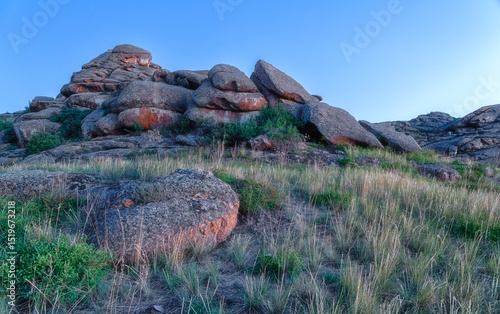 Huge stone standing rocks in green jungle with lush vegetation at dawn flooded with morning sun. Kazakh expanses, Mount Ku Egendybulak. Summer autumn landscape