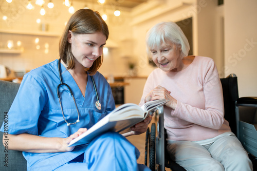 Wallpaper Mural Female care assistant reading a book to a elderly lady and both looking enjoyed Torontodigital.ca