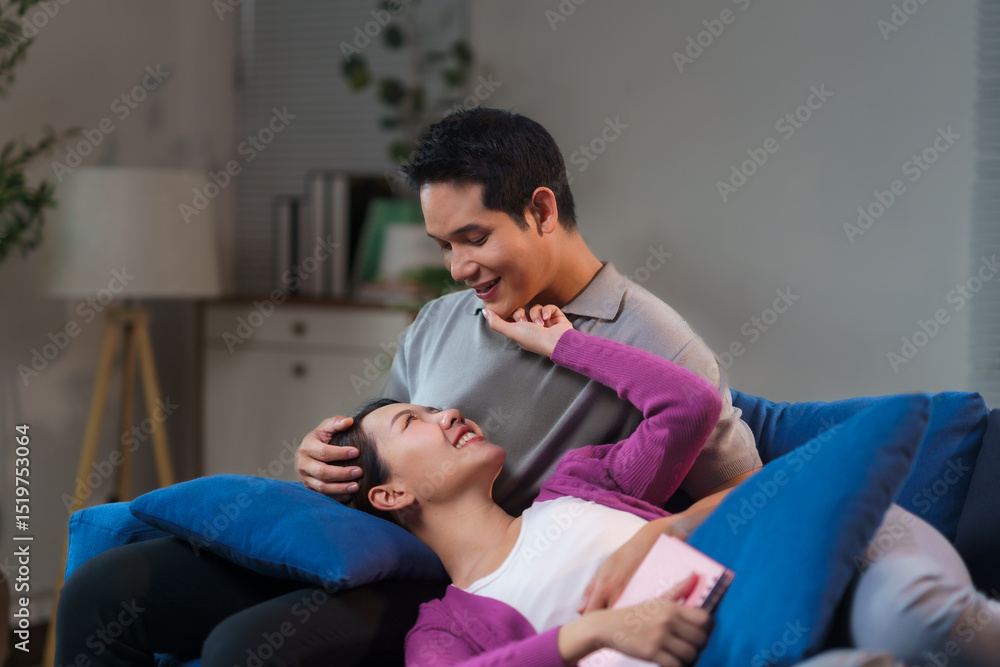 Obraz premium Young asian couple relaxing on sofa, showing love and bonding at home, lying on her boyfriend's lap