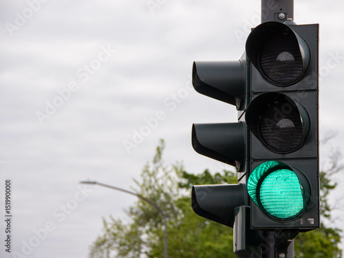 Foto Black traffic light with a bright green signal illuminated, symbolizing go-ahead, urban transportation control, and safe road navigation