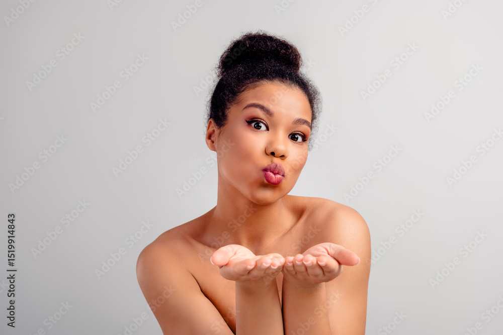 Obraz premium Portrait of a beautiful young woman blowing a kiss with a natural and elegant look on a light background