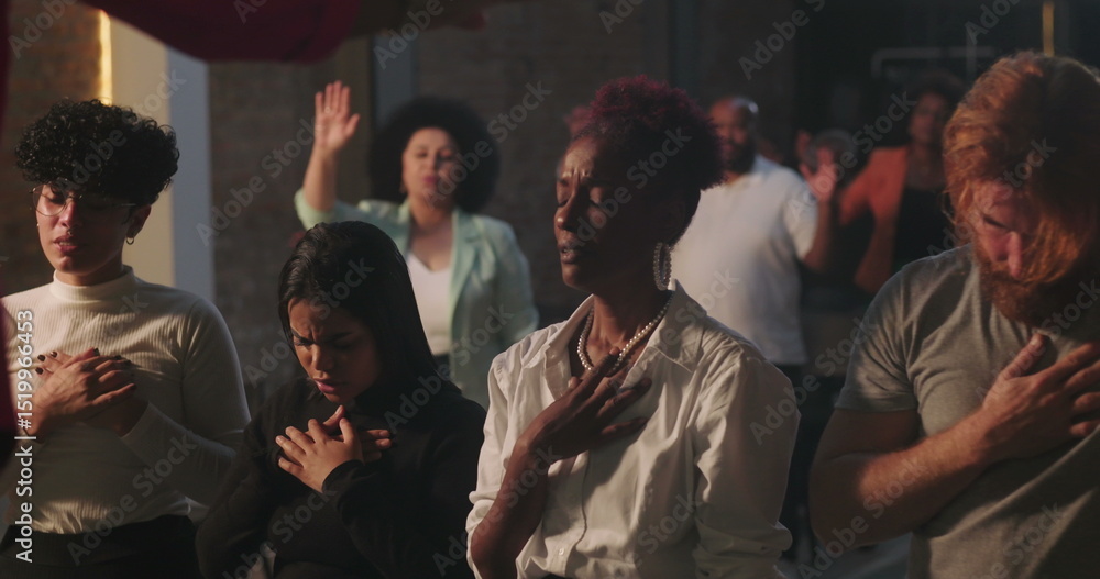 Fototapeta premium Diverse congregation praying with hands on hearts, emotional worship moment emphasizing unity, faith, and devotion during spiritual gathering in sacred Christian setting