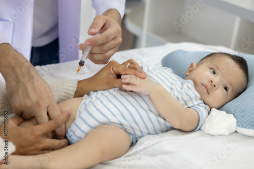 A baby is being vaccinated by a doctor, with the mother closely caring for the baby lying on the bed and the doctor holding a syringe.
