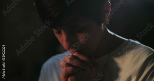 Tableau sur toile Woman bowing head in prayer, hands clasped in silent spiritual reflection, peace
