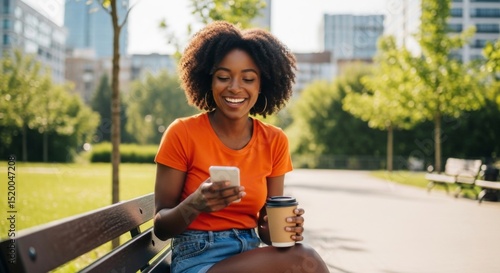 Fototapeta Naklejka Na Ścianę i Meble -  Young woman enjoying a sunny day in the park with coffee and smartphone