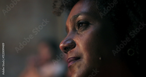 Close-up of woman with curly hair, emotionally moved during spiritual moment in church, illuminated cross in background, contemplation, deep faith connection
