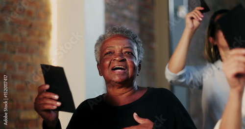 Elderly African woman holding offering envelope during church worship, joyful expression, diverse congregation in background, moment of spiritual faith and unity in sacred space