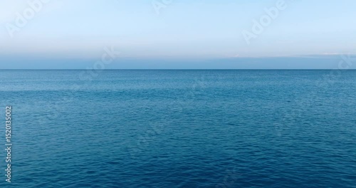 Aerial shot over the empty blue sea during sunset. Aerial ocean view at blue hour.