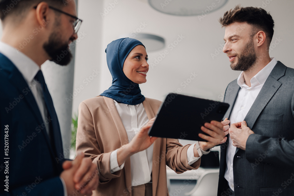 Muslim businesswoman showing digital tablet to colleagues in office meeting Muslim businesswoman showing digital tablet to colleagues in office meeting