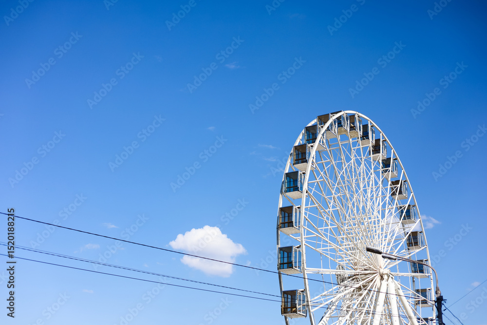 Ferris wheel under clear blue sky at local amusement park on sunny afternoon