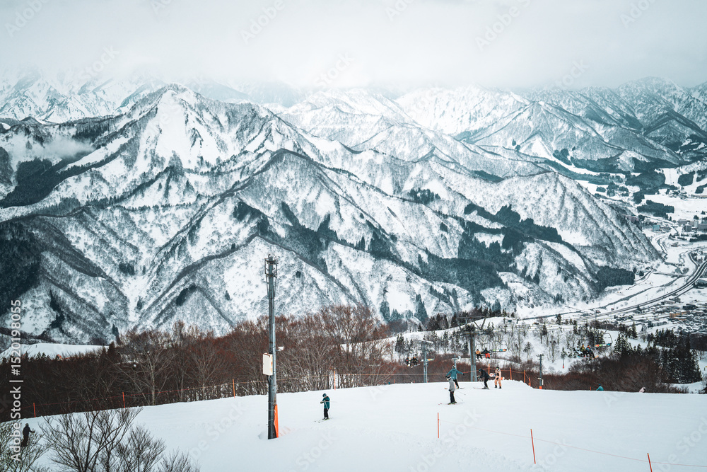 Obraz premium A breathtaking panoramic view of snow-covered mountain ranges including Ishiuchi Maruyama, Yuzawa Kogen, and distant peaks near Echigo-Yuzawa in Niigata, Japan, captured from Gala Yuzawa station.