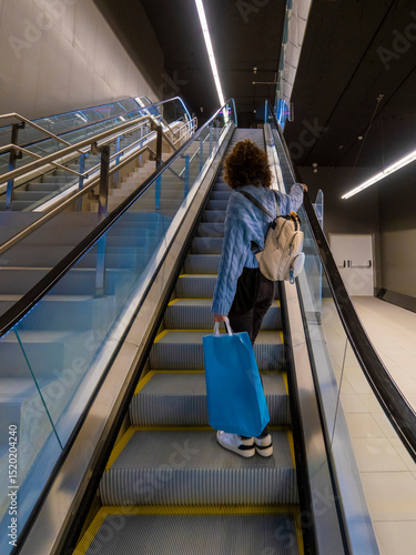 View of a girl going up escalator with shopping bag