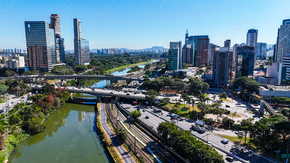 Fototapeta premium Visão aérea do bairro de Pinheiros e do Rio Pinheiros, em São Paulo, SP. A imagem mostra a região urbana com prédios, vias movimentadas e o rio cortando a cidade em meio ao cenário metropolitano