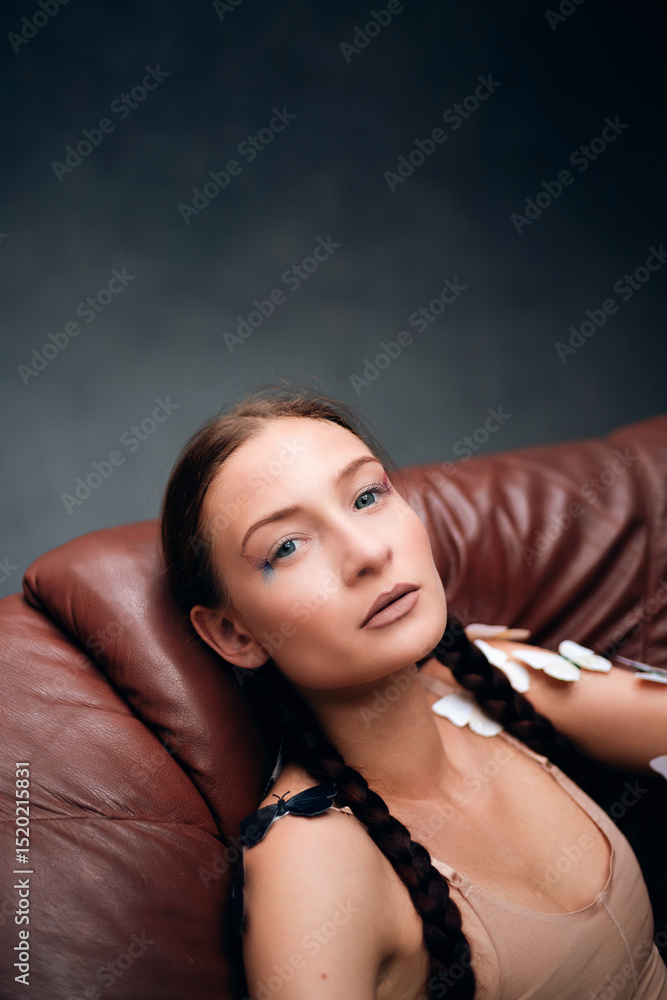 A model poses in a stylish leather chair during a studio photoshoot. Soft lighting A model poses in a stylish leather chair during a studio photoshoot. Soft lighting