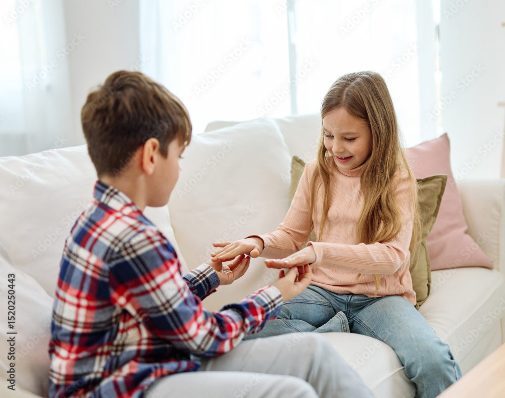 Obraz premium Portrait of sister and brother, girl and boy, teenagers, having fun together playing a game with hands at home