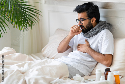 Papier peint Sick Young Indian Man Coughing While Sitting In Bed At Home, Ill Millennial East