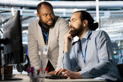 Fotografija Data center manager supervising work done by employee verifying neural network parameters