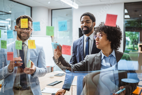 Photos Coworkers brainstorming and planning use sticky notes on glass wall