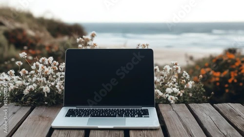 Laptop on wooden platform by the ocean, showcasing remote work and digital nomad lifestyle