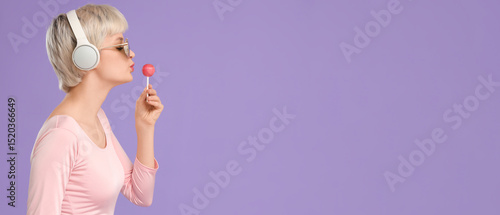 Portrait of beautiful young woman with sunglasses, headphones and lollipop on...
