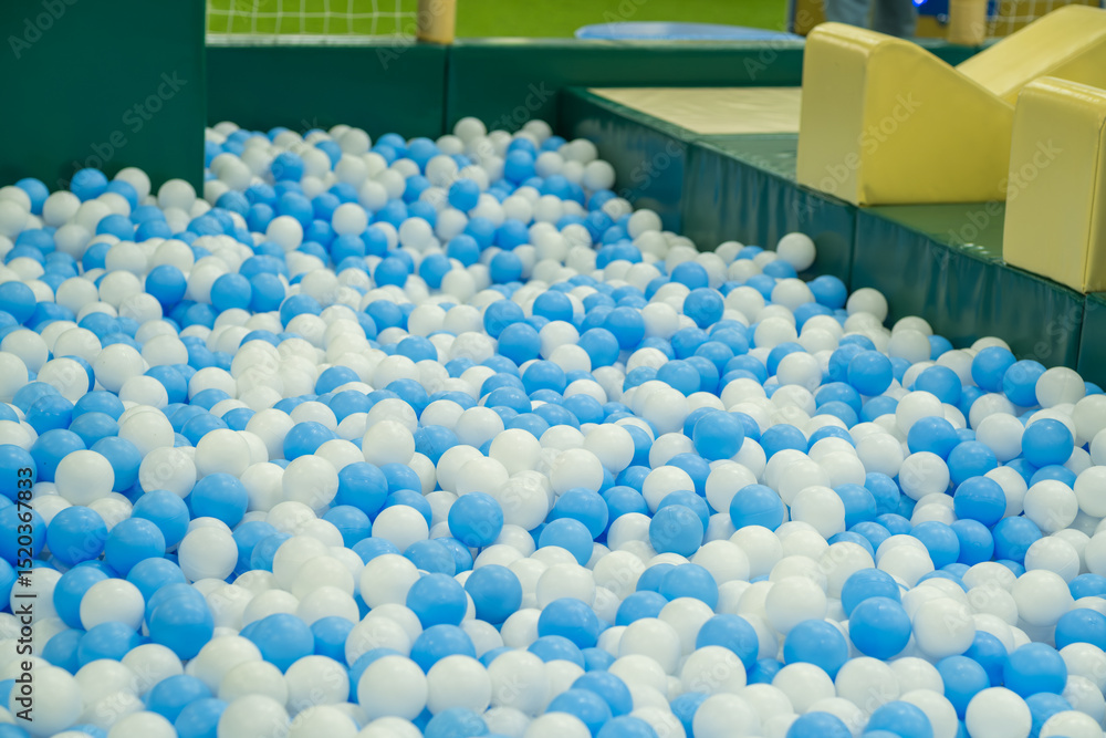 Obraz premium A vibrant indoor play space features a large ball pit filled with blue and white balls.
