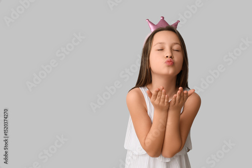 Little girl in crown blowin...