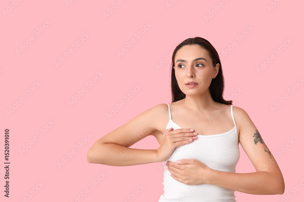 Young woman checking her breast on pink background. Cancer awareness concept Young woman checking her breast on pink background. Cancer awareness concept
