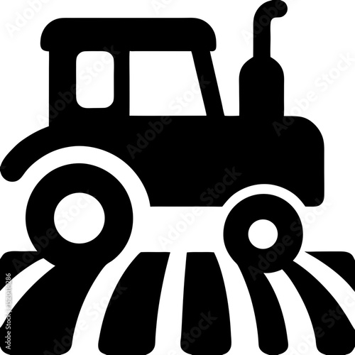 Black silhouette of a tractor on plowed field