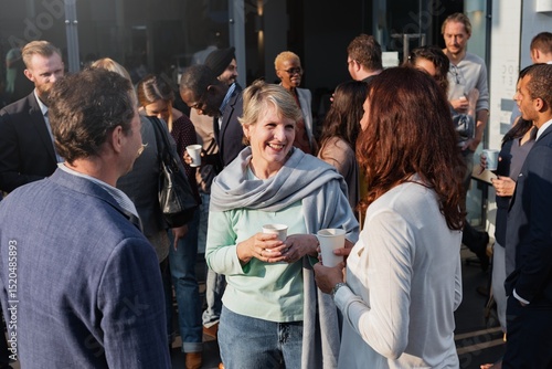 Fotografie Group of diverse adults socializing outdoors, holding coffee cups