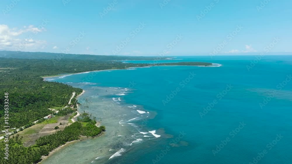 Tropical island with white sand shoreline and beautiful waves in coast. Blue skies and clouds. Mindanao, Philippines. Tropical island with white sand shoreline and beautiful waves in coast. Blue skies and clouds. Mindanao, Philippines.